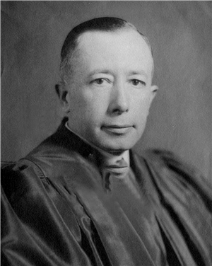 Head and shoulders portrait of a white man in a judge's robe